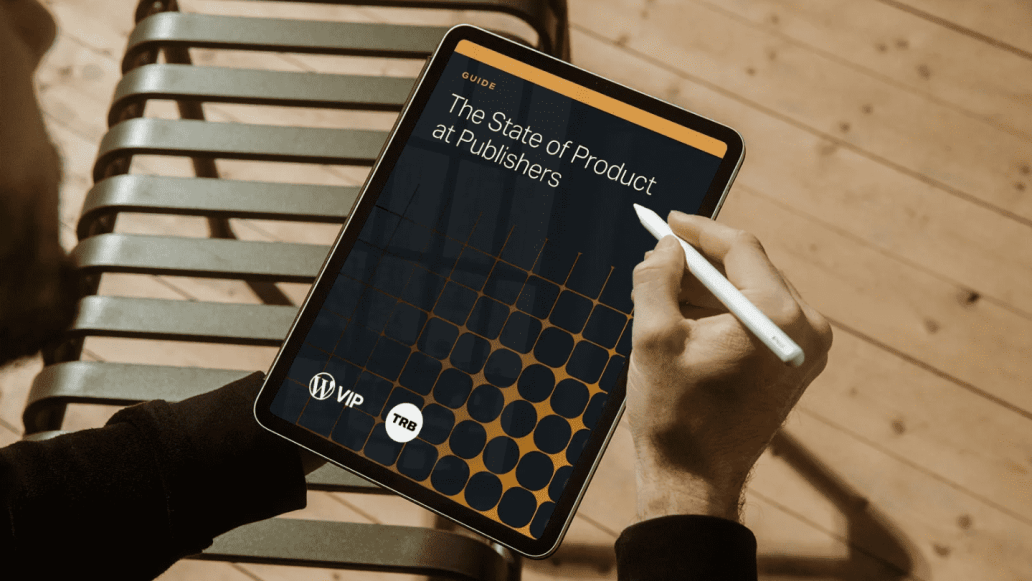 Person holding a tablet and stylus, viewing a digital guide titled “The State of Product at Publishers.” The tablet screen displays branding for WordPress VIP and The Rebooting, with a dark background and geometric orange pattern.